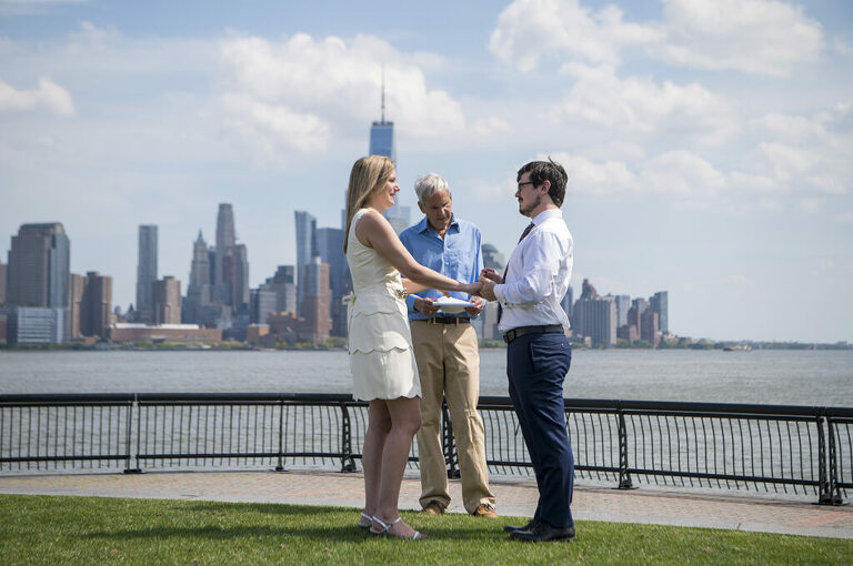 Wedding couple exchanges rings during their socially distanced micro wedding ceremony on Pier A in Hoboken
