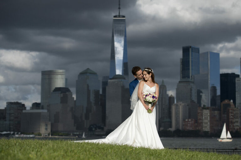 bride and groom pose for portrait against NYC skyline before their wedding ceremony at Liberty House in Jersey City