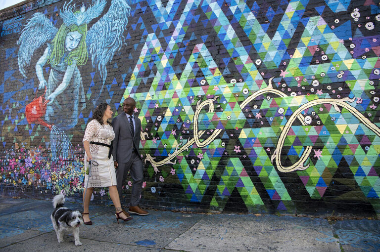 wedding couple with their dog in front of mural in Welling Court