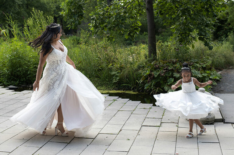 bride and her flower girl twirl in their dresses at Queens Botanical Garden