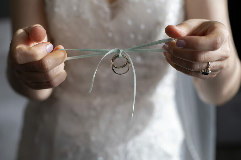 bride holds wedding rings tied together