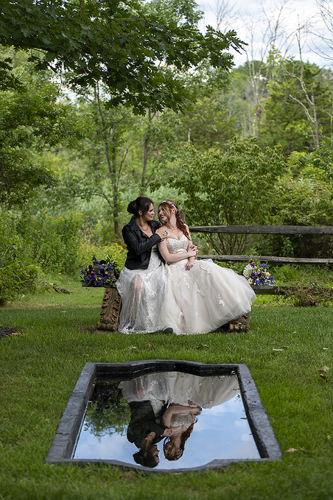 brides sitting at reflecting pool at Crossed Keys Estate Wedding