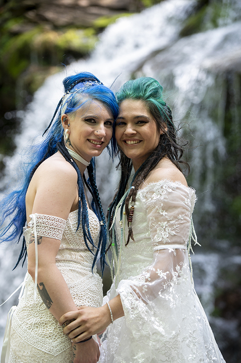 brides at waterfall in the forest on their wedding day at Riedlbauer’s Resort in the Catskills. LGBTQ wedding