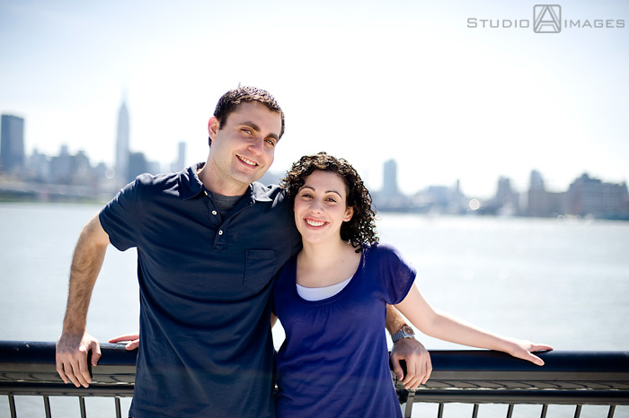 engaged couple in front of NYC skyline during their Hoboken engagement session