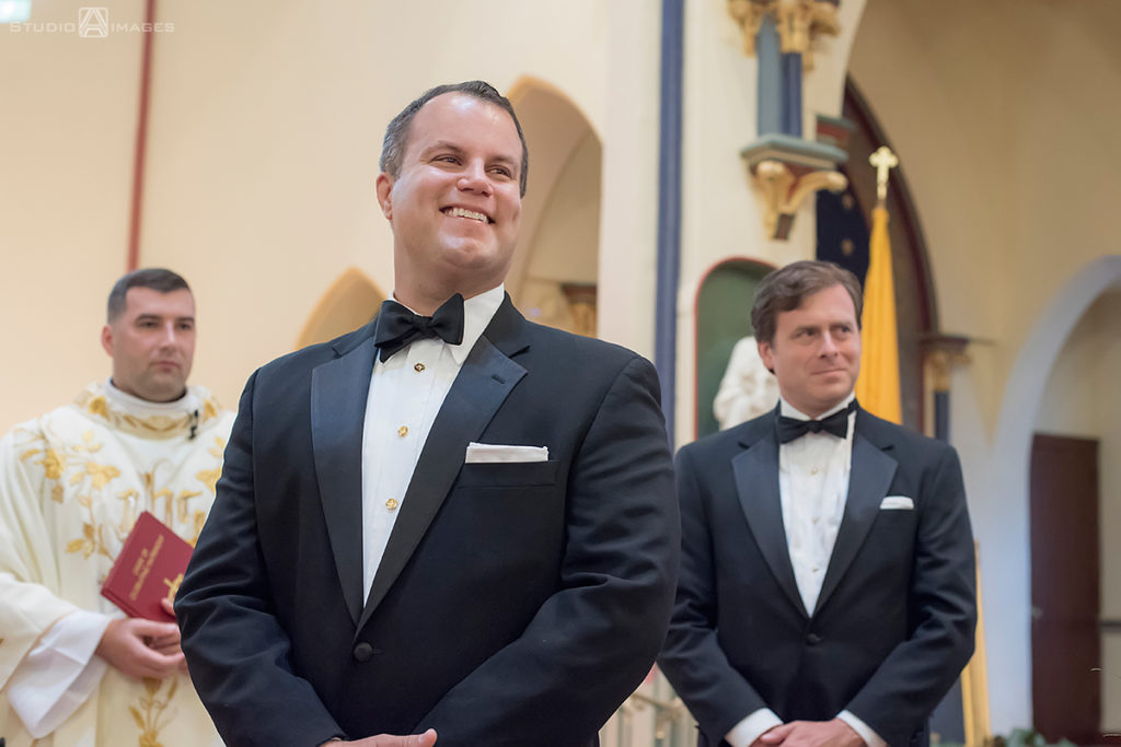 groom watching as his bride walks down the aisle on their wedding day