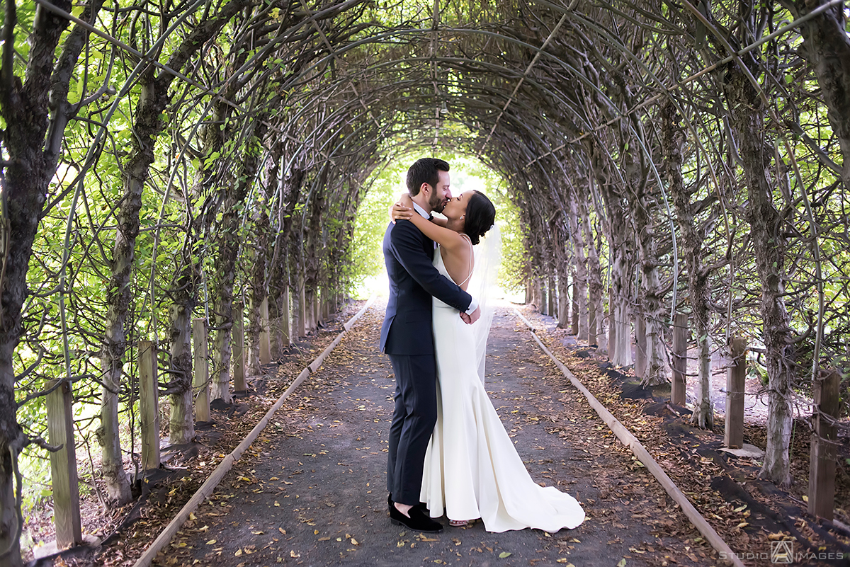 couple kisses in the allee at Celebrate at Snug Harbor on their wedding day