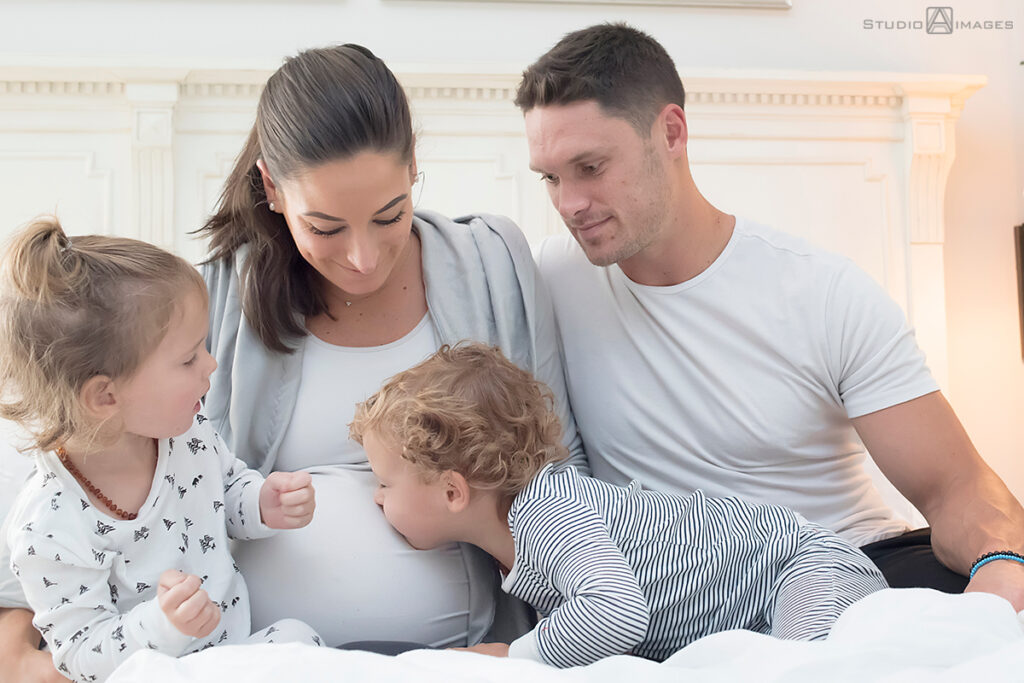 Long Island family photos with kids kissing pregnant mom
