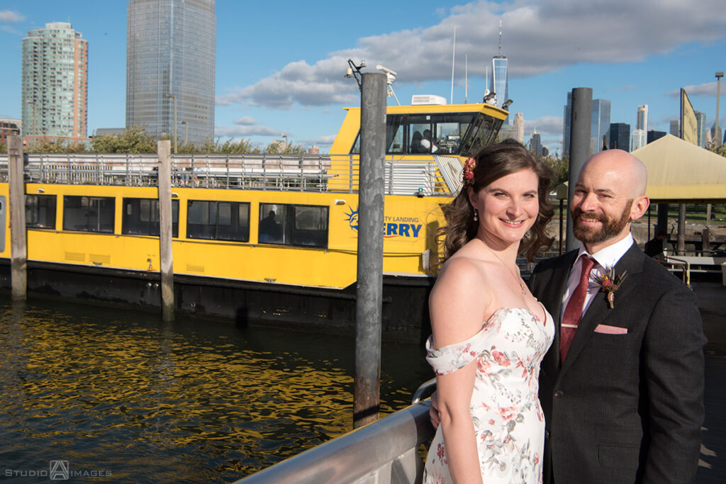 bride and groom posing for portraits with the ferry before their wedding at Liberty House in Jersey City