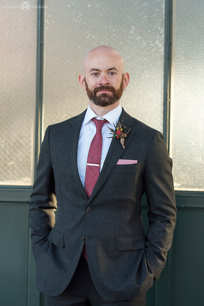 groom posing for portraits in Liberty State Park before their wedding at Liberty House in Jersey City