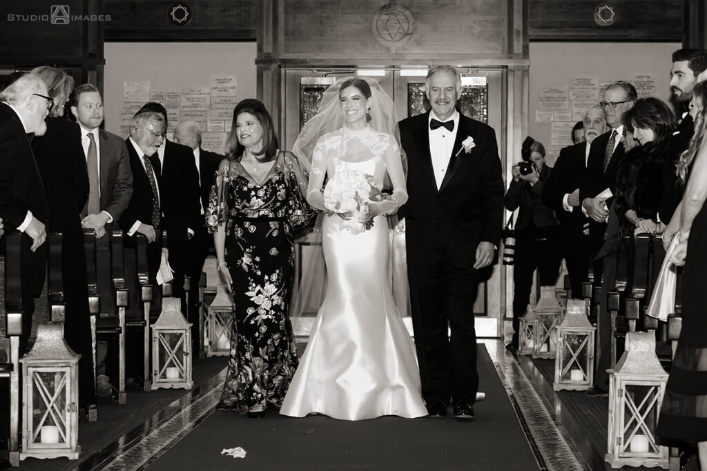 bride walking down the aisle with parents for wedding ceremony at Temple Emanu-El of Closter
