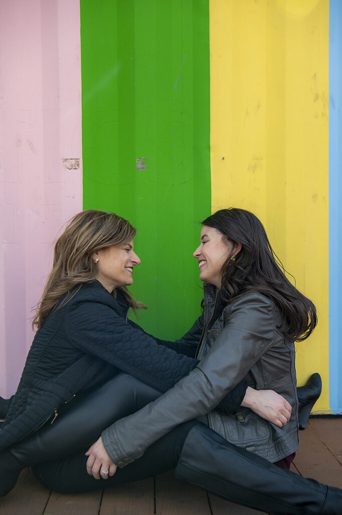 LGBTQ couple embracing against colorful wall during their Philadelphia Engagement Session
