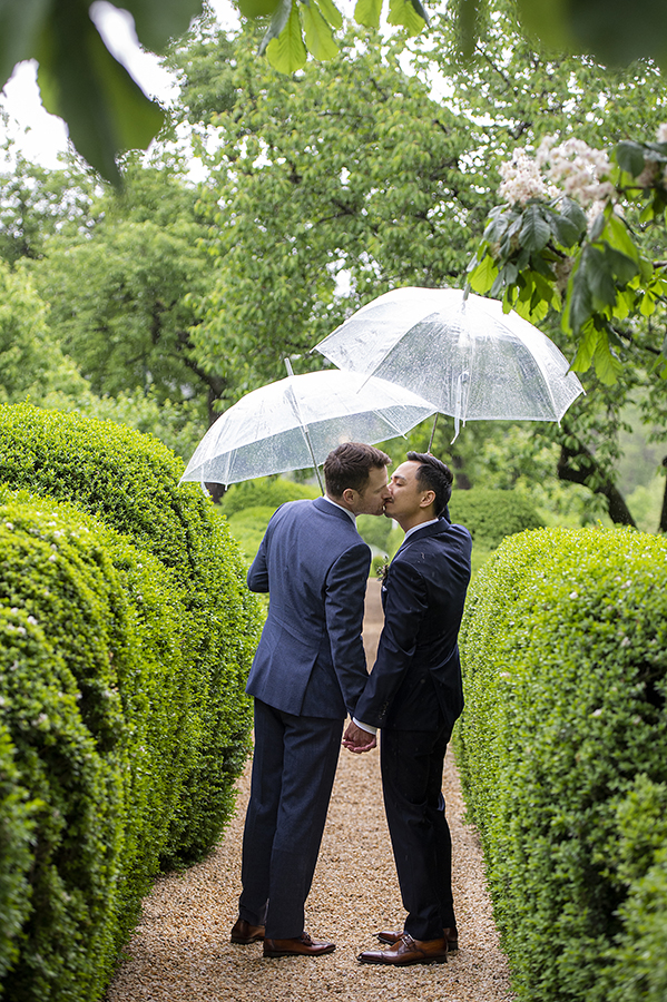 two grooms on wedding day at Liberty Hall Museum with umbrellas