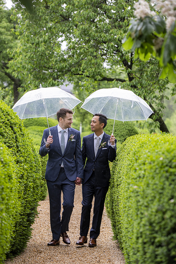 two grooms on wedding day at Liberty Hall Museum with umbrellas