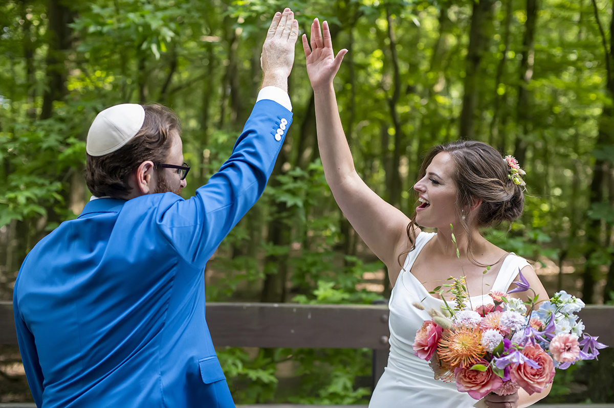 bride and groom high fiving at Temple Emanu-El of Closter on their wedding day