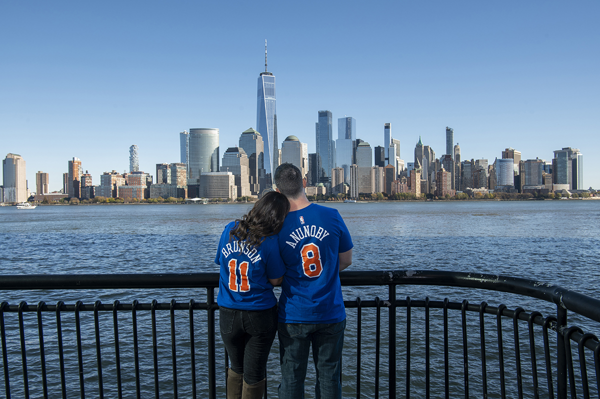 engaged couple wearing Mets Jerseys with NYC skyline behind them