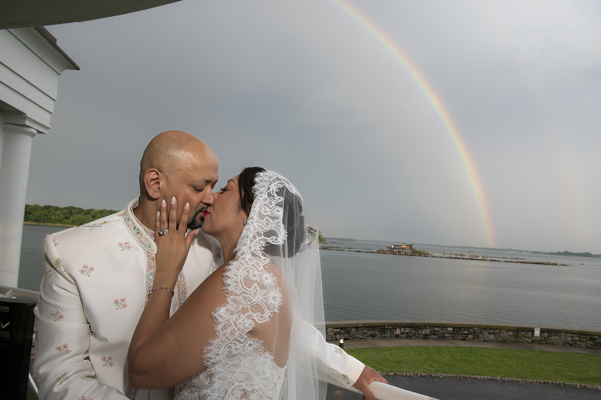 bride and groom kissing with a rainbow at their Glen Island Harbour Club wedding